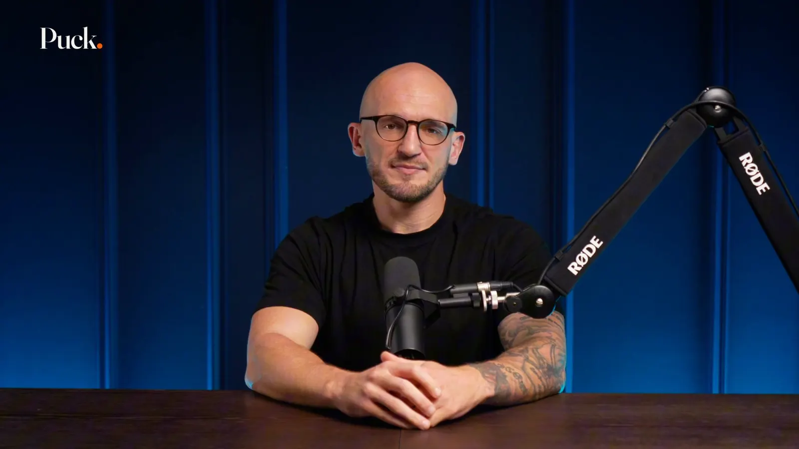 Adam Callow, Co-founder of Puck, at a desk in front of a navy curtain.